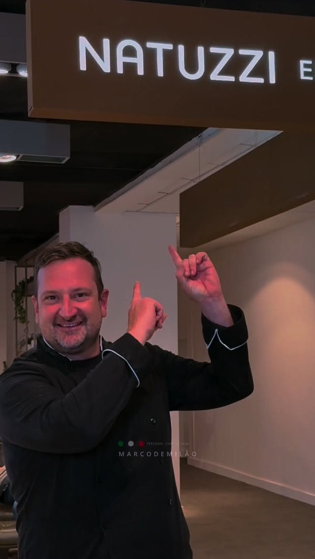 Chef Marco de Milão apontando para a placa da Natuzzi no congresso anual da marca
